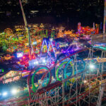 A sweeping bird's-eye view showcases a winter wonderland, with the colourful rides and winter market